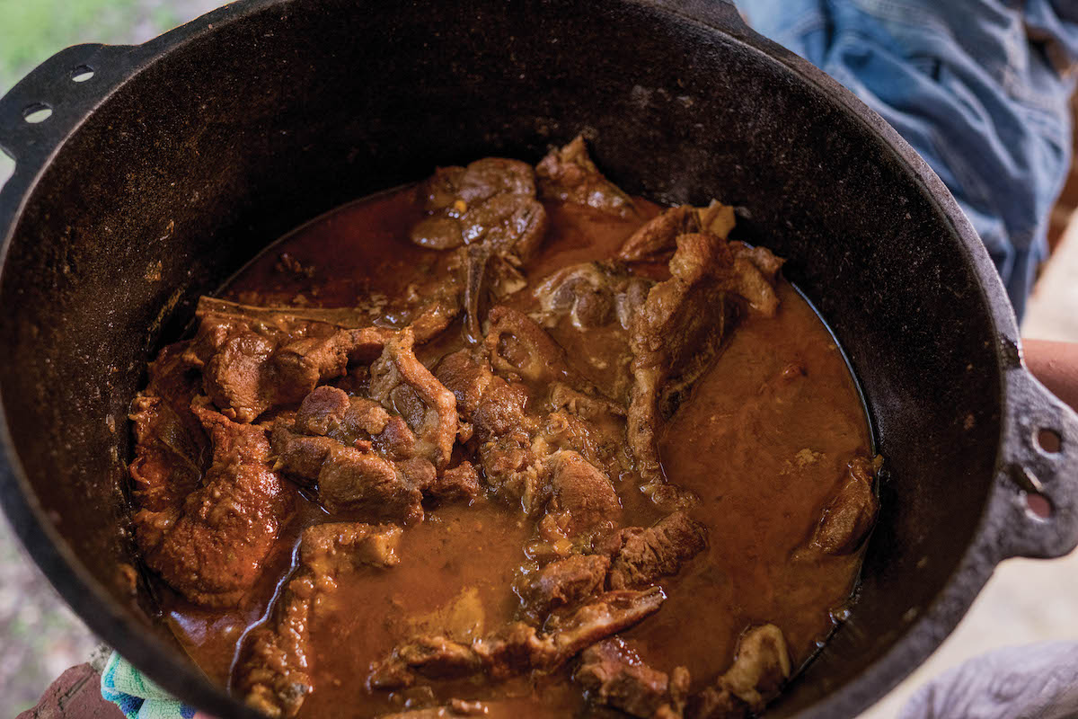 A cast iron pot filled with pork steak and gravy