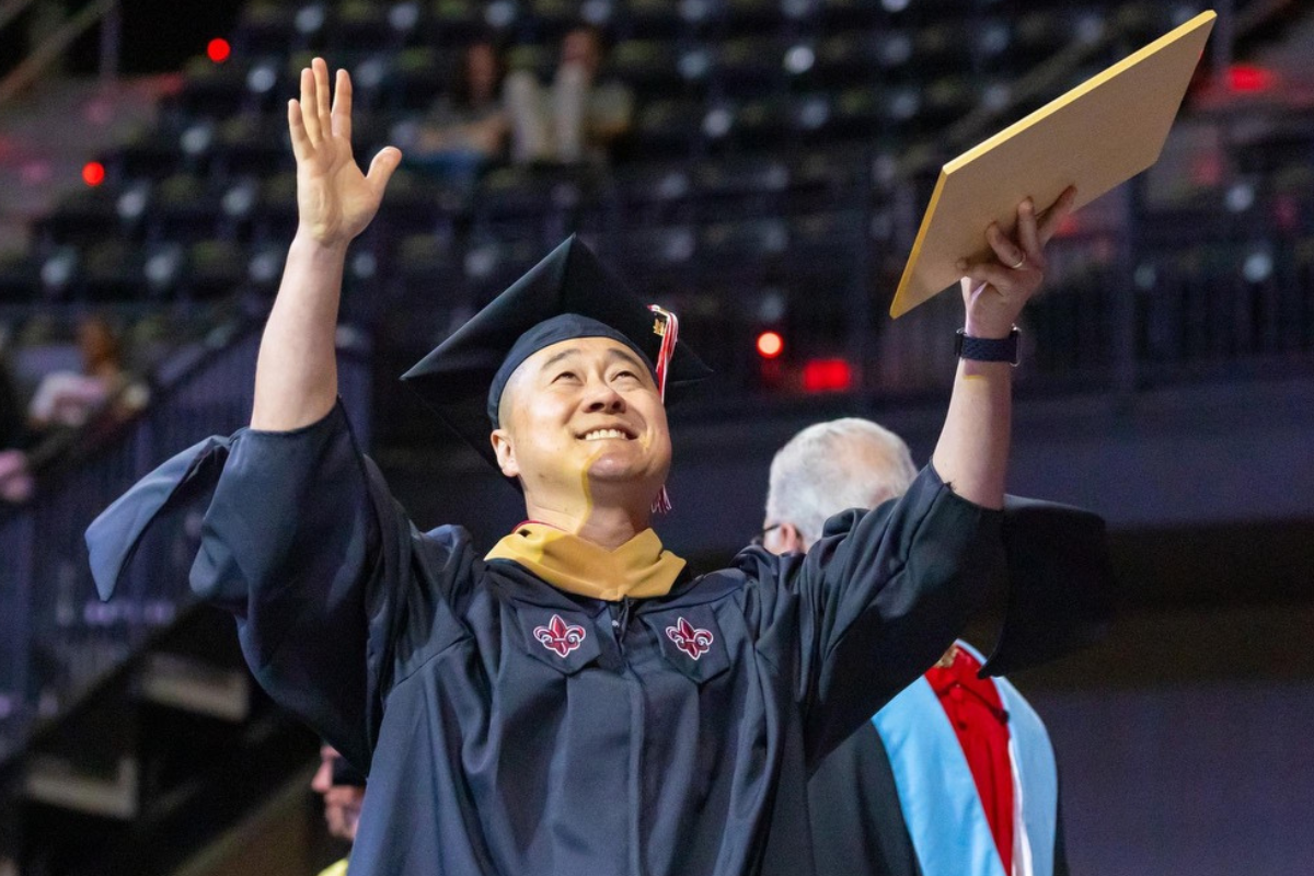 master's graduate holding hands up to the sky 