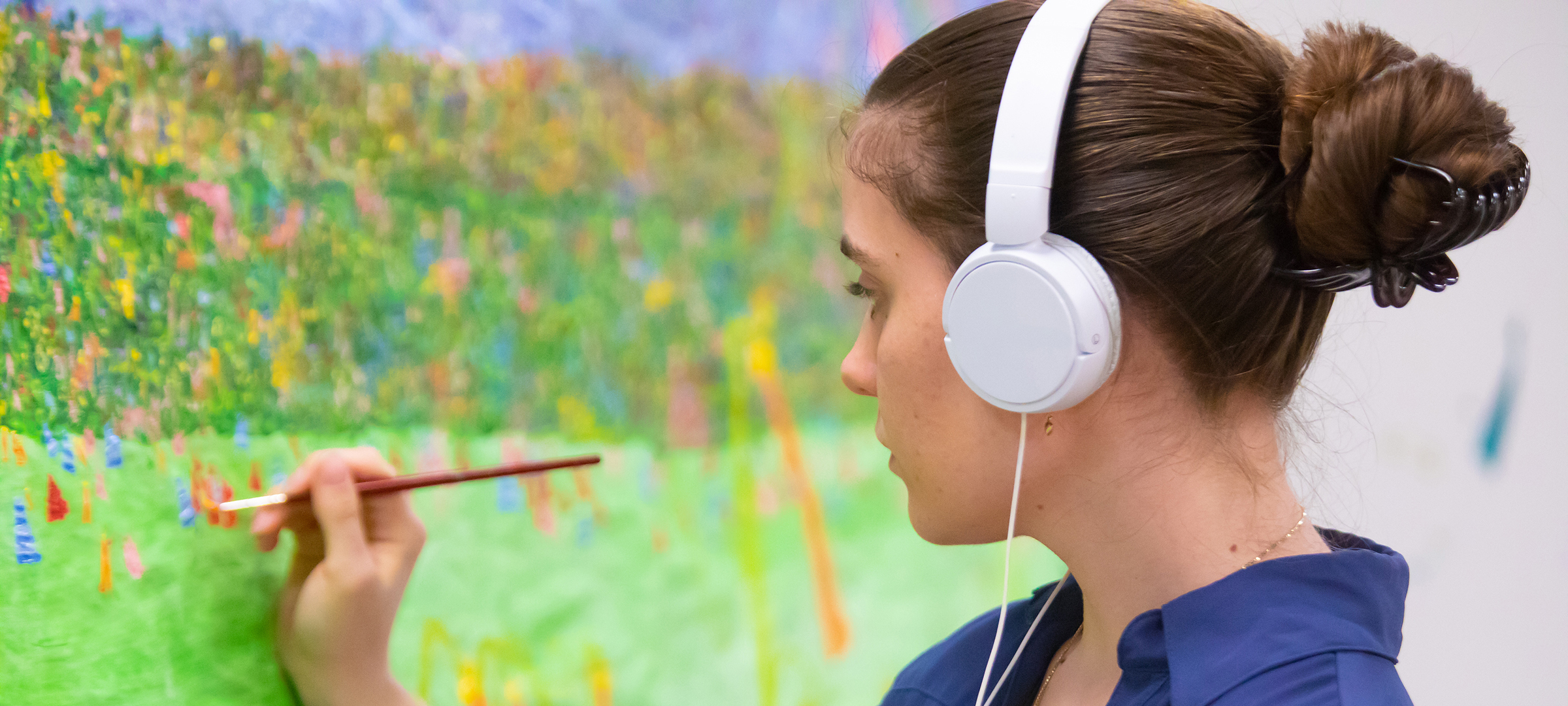 UL student paints flowers in a field on a brighly colored canvas