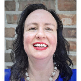 Headshot: Colleen Wolverton pictured in front of a brick wall.