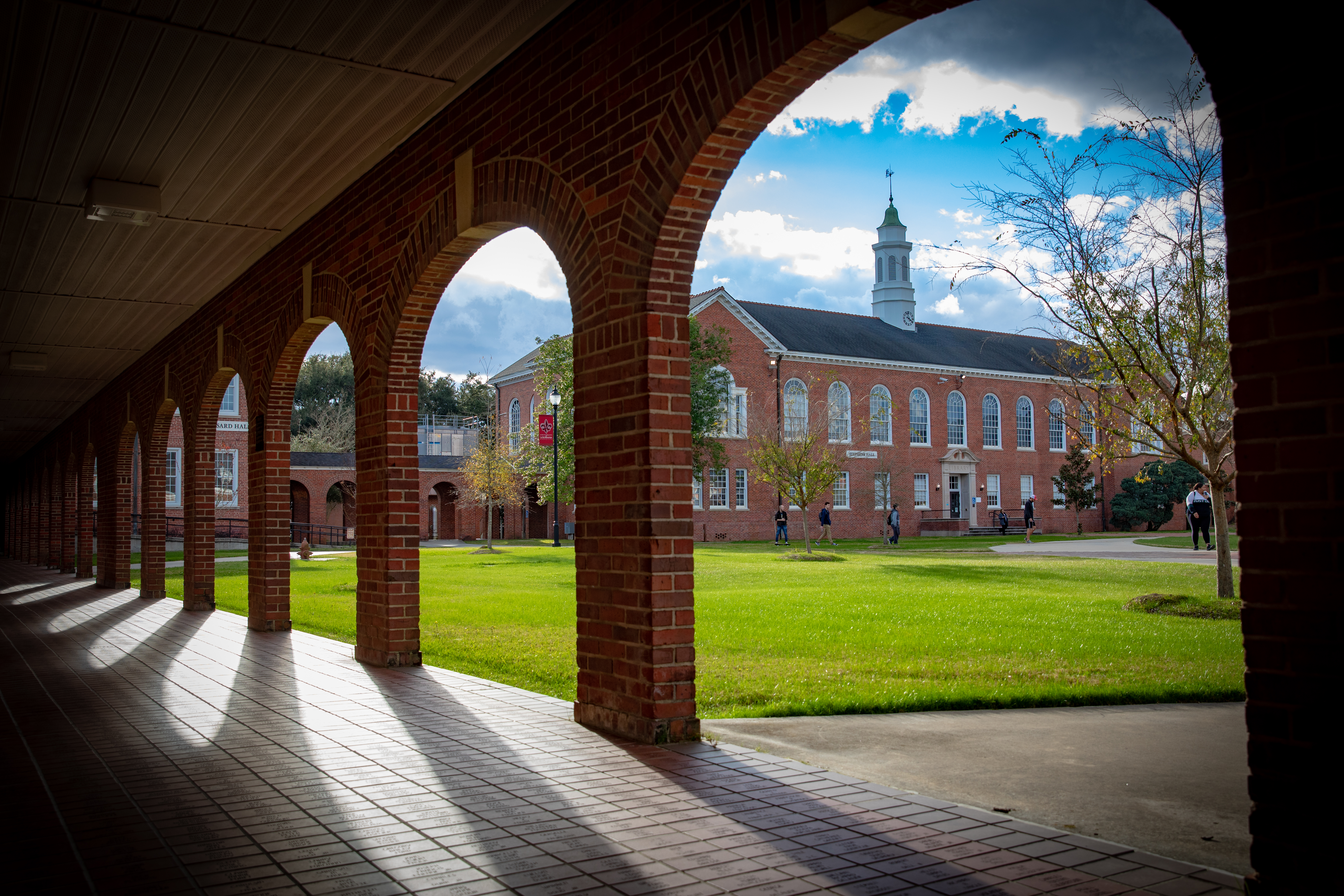 Stephens Hall in the UL Lafayette quad, viewed through the brick arches of the Walk of Honor