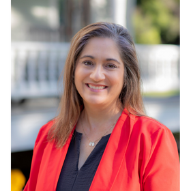 Headshot: Tarrah Davis is pictured outdoors wearing a black blouse and red blazer