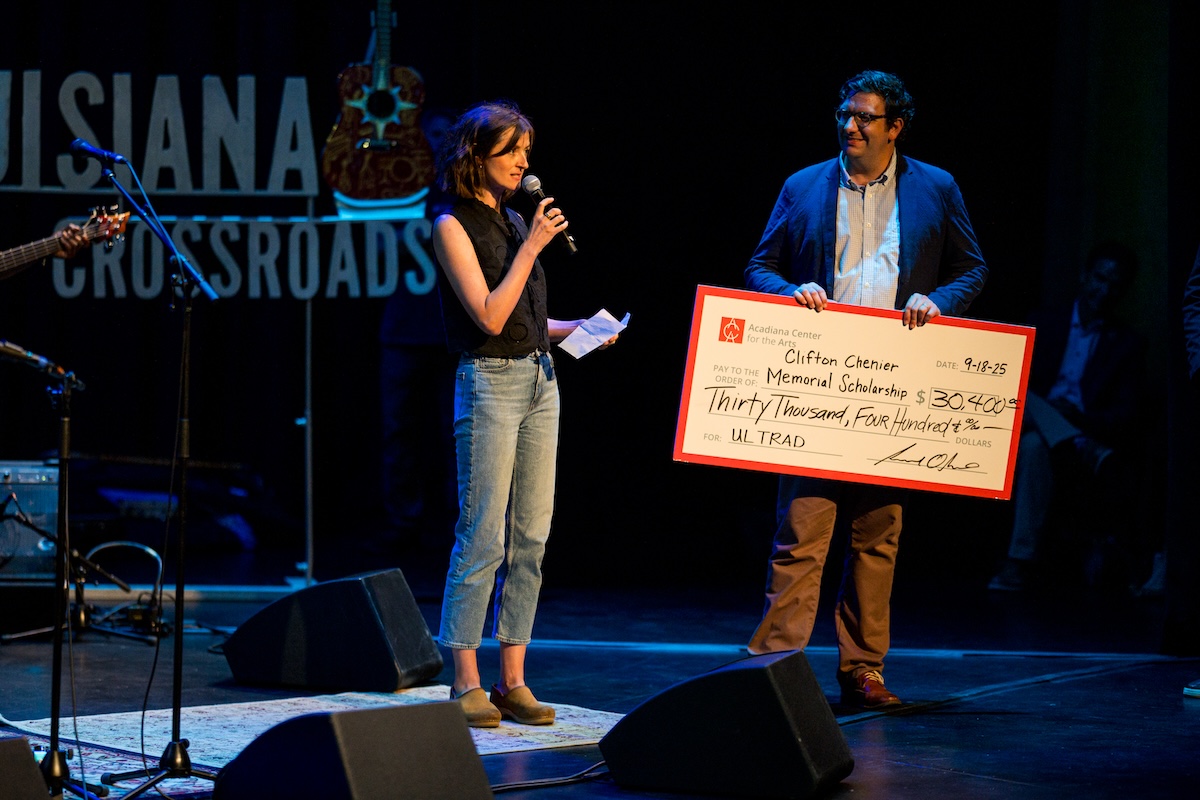 Director of the Acadiana Center for the Arts, Sam Oliver, hands a giant check for $30,000 to Dr. Gwendolen von Einsiedel, the second holder of the Dr. Tommy Comeaux Endowed Chair, on stage at a sold-out concert at the Acadiana Center for the Arts.