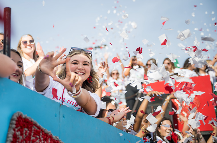 UL Lafayette Kappa Delta sorority member smiling on a parade float with confetti all around her.