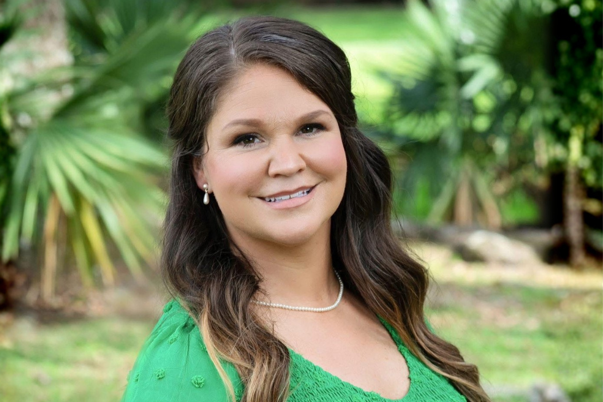 Graduate of the hybrid MEd Educational Leadership program smiles in a nature setting.