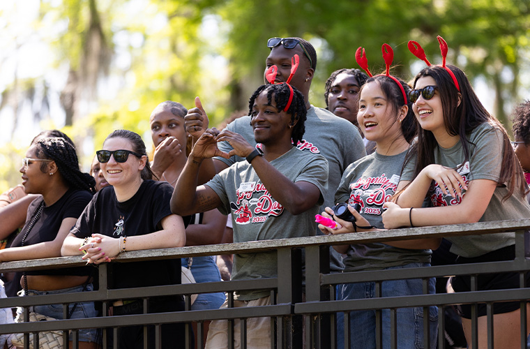 UL Lafayette students wearing crawfish claw headbands watching Lagniappe Day canoes