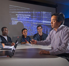 A group of men sit around a conference table discussing a data mining presentation. 