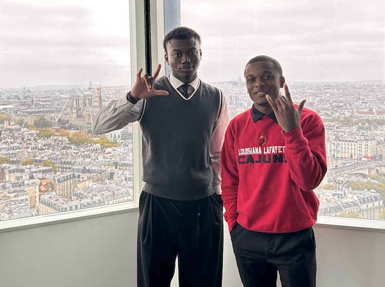 Two UL Lafayette students stand near a window in Paris overlooking the city.