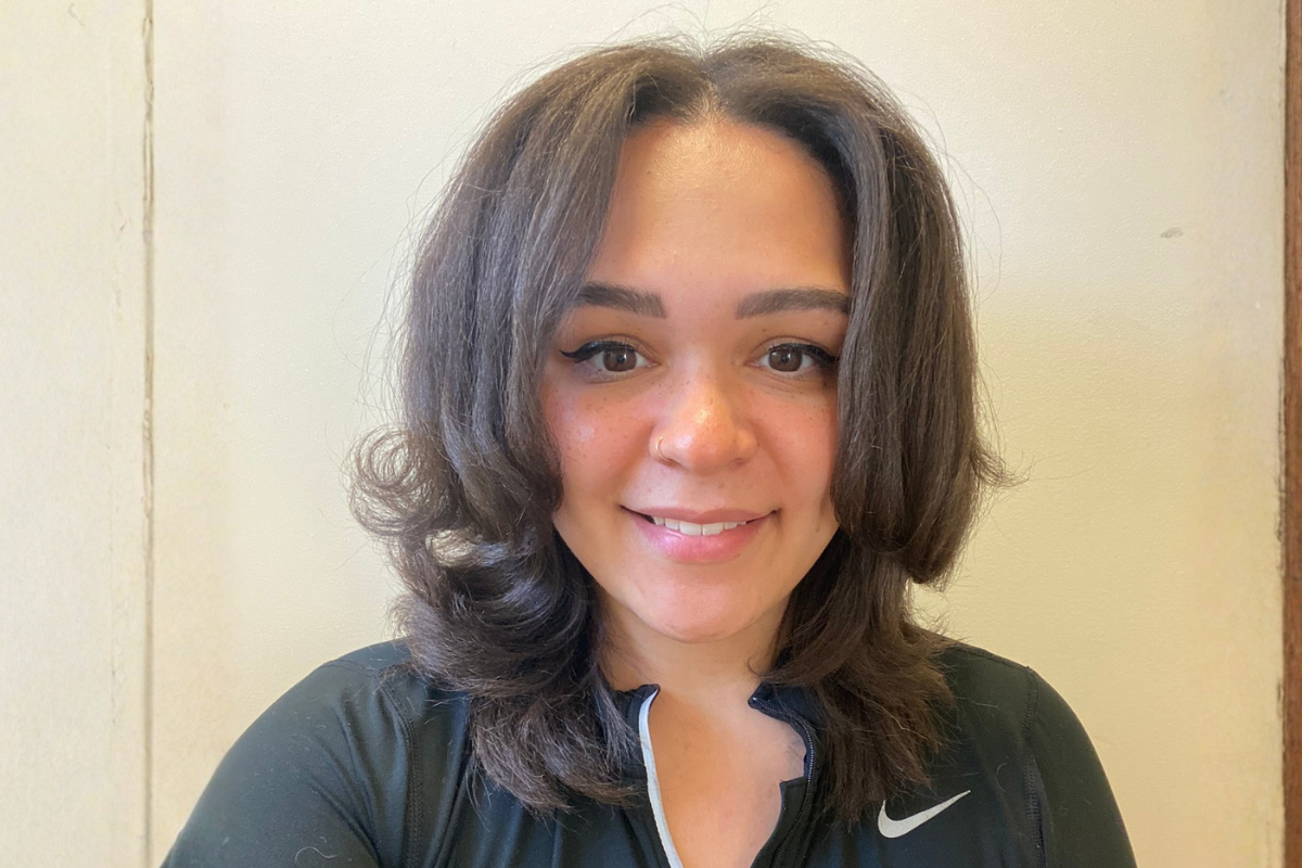 RN to BSN online alumna smiles wearing a black quarter-zip jacket.