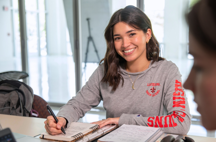 UL Lafayette psychology student studies online wearing a grey Ragin' Cajuns t-shirt.