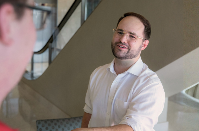 Masters in HR graduate smiles while shaking hands with a colleague. 