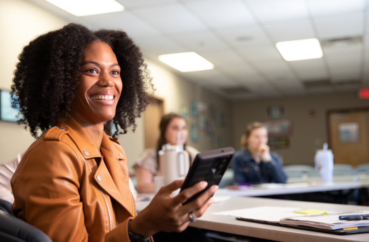 Health Promotion & Wellness online degree alumna Terri Roberts smiles across a conference table in the Foundation for Wellness offices.