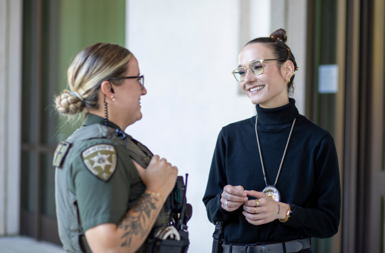 Two female officers with the Lafayette Parish Sheriff's Office stand facing each other.
