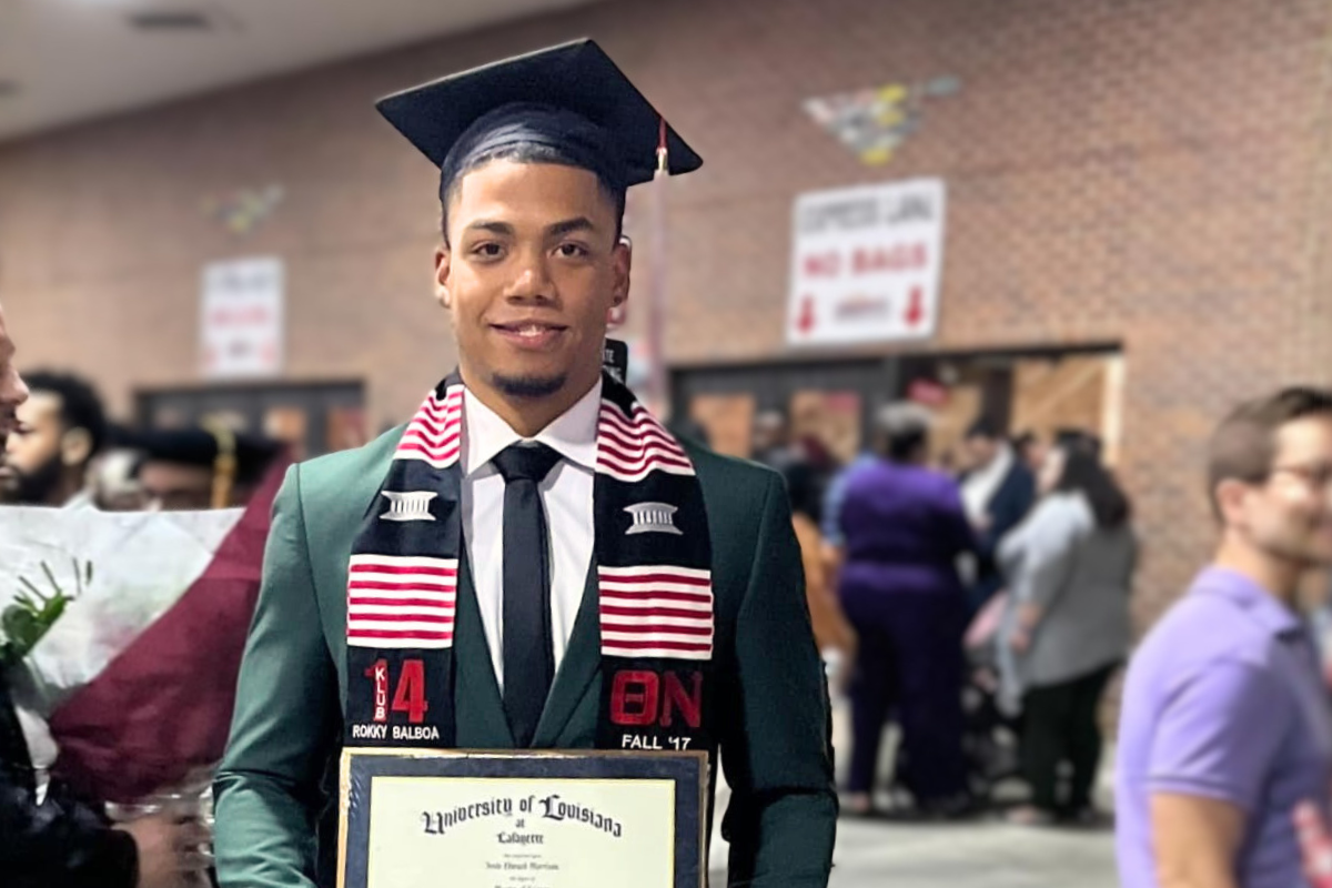 MS in Engineering Tech online graduate smiles while holding his diploma after Commencement Ceremonies.