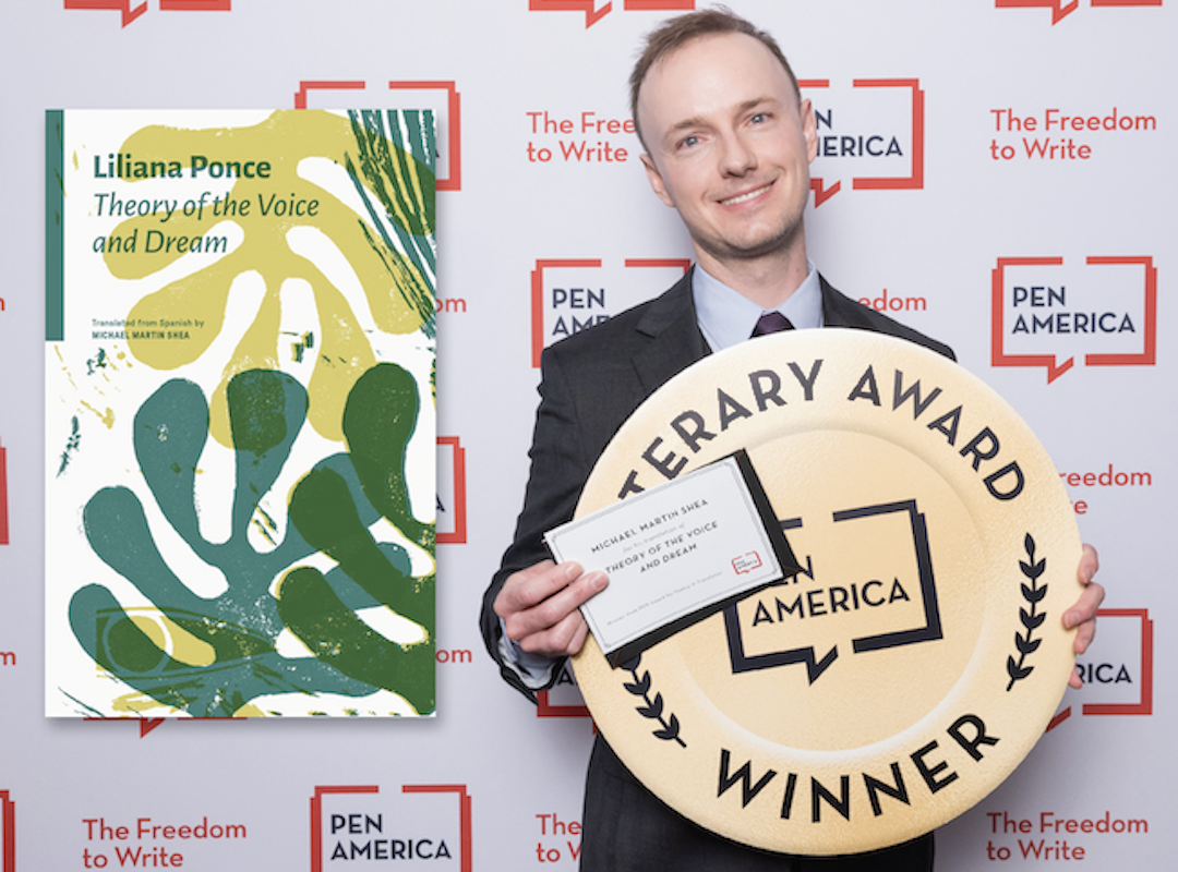 A man holds a certificate and a large circular award medallion.