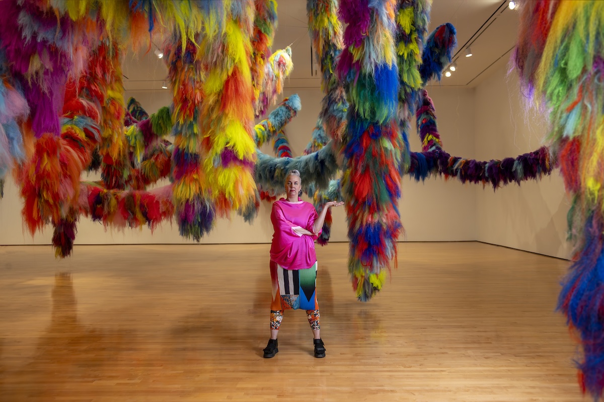 Artist Hrafnhildur Arnardóttir (aka Shoplifter) with their work Nervescape VII, a colorful, tactile art installation at the Hilliard Art Museum.