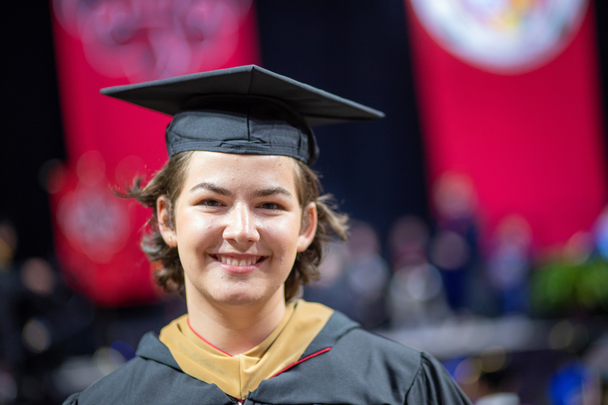 M.S. in Accounting graduate Debra Crawford smiles during commencement ceremonies. She's wearing black, UL Lafayette commencement regalia.