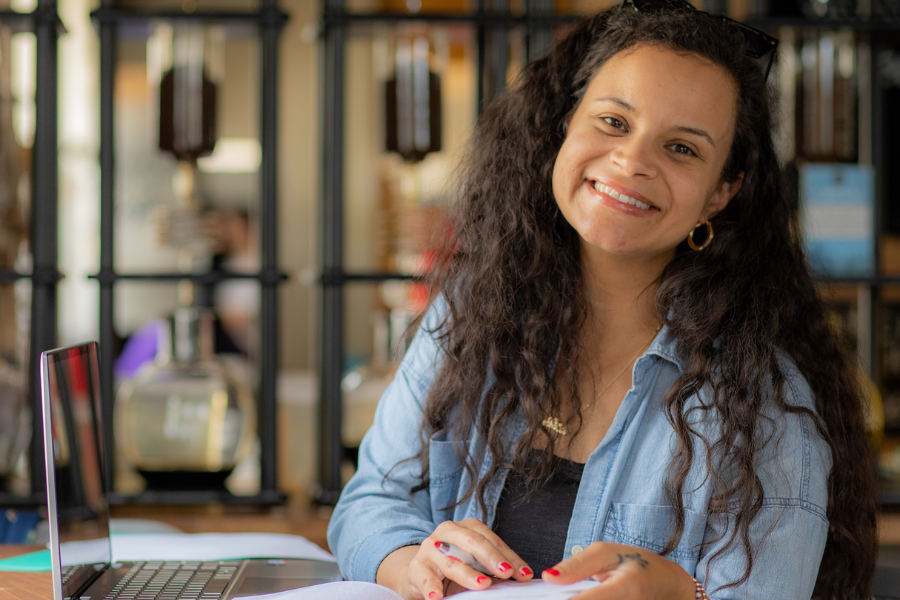 RN to BSN graduate Jaime Taylor smiles over her textbook and laptop.