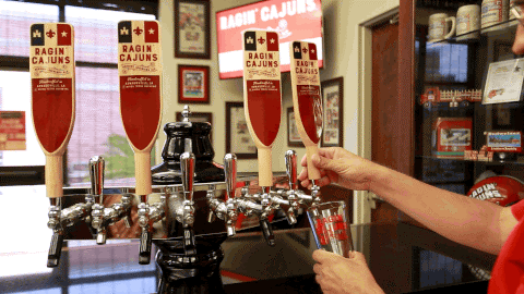 A hand behind the bar at a local brewery pouring tap beer