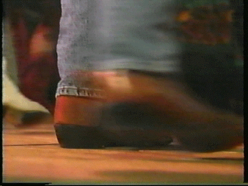 the bottom of a persons pants leg showing cowboy boots dancing on a dance floor