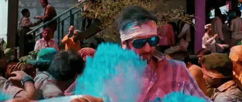 a man dancing in a crowd in holi fest covered in color