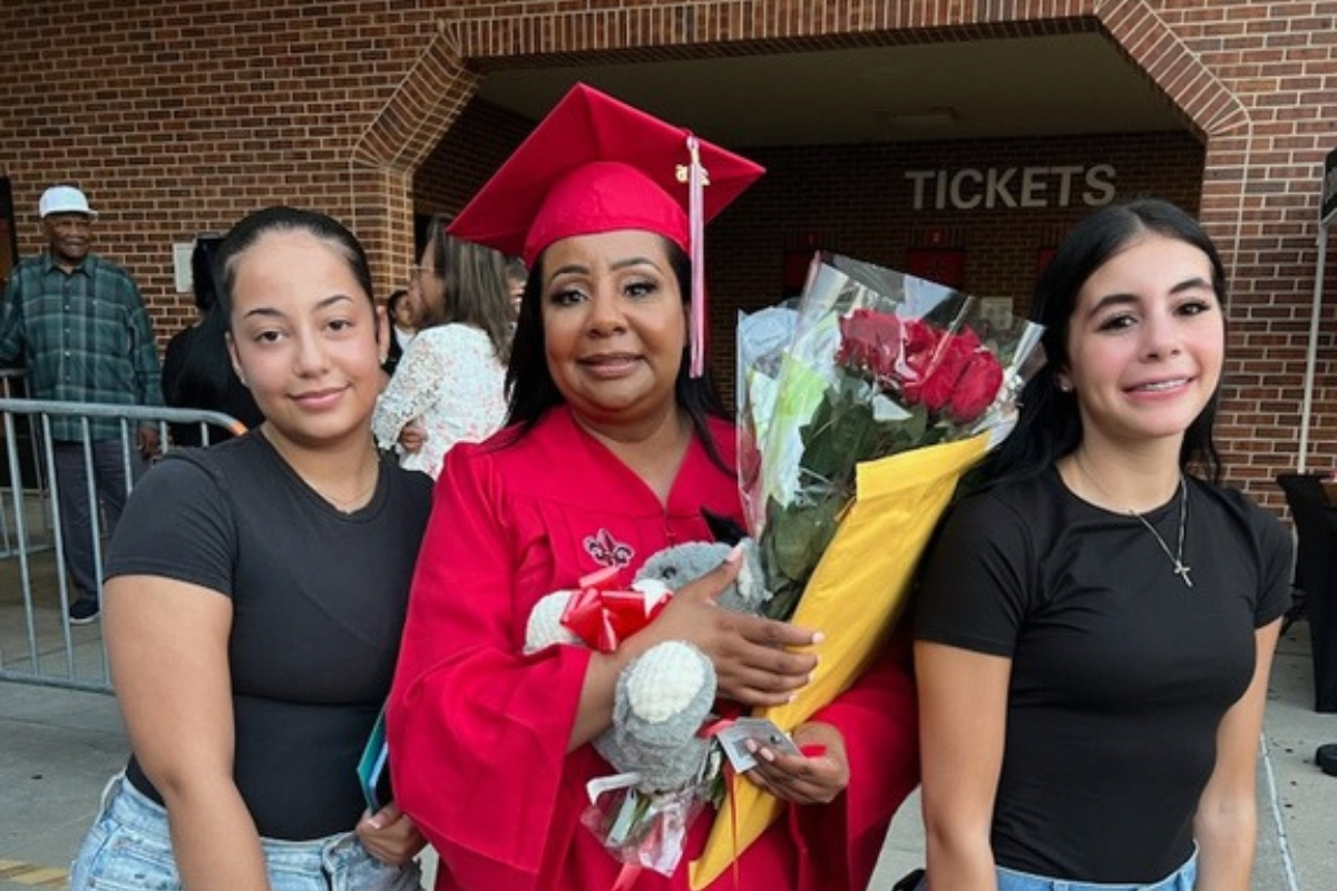 Chandra Cousin smiles with her two daughters after earning her online general studies degree, wearing a red UL Lafayette cap and gown.