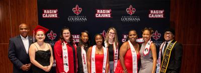 A group of LEP graduates wearing graduation stoles pose with Dr. DeWayne Bowie