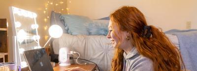 UL Lafayette Student working on her computer in a dorm room.