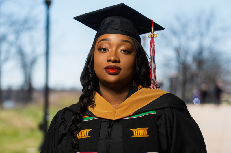UL Lafayette online MBA grad poses in black graduation regalia. 