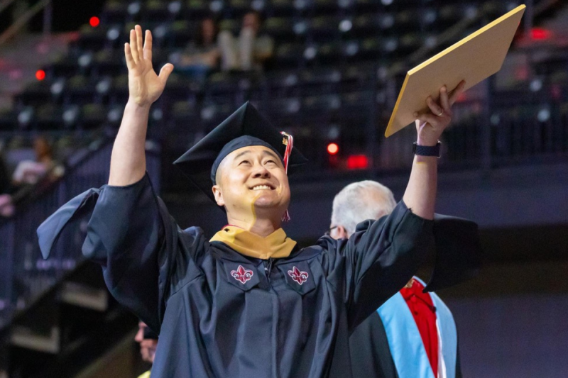 master's graduate holding hands up to the sky 