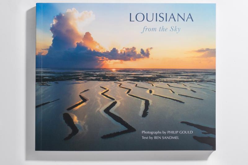 The cover of the book "Louisiana from the Sky" featuring an aeriel view of a flooded landsape and a setting sun through the clouds.