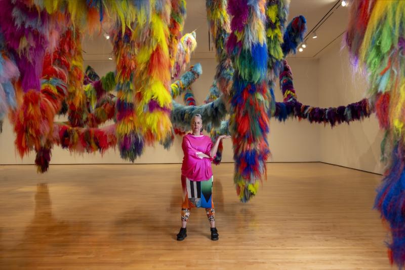 Artist Hrafnhildur Arnardóttir (aka Shoplifter) with their work Nervescape VII, a colorful, tactile art installation at the Hilliard Art Museum.
