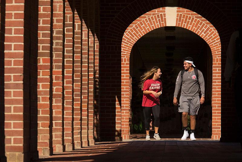Two University of Louisiana at Lafayette students walking through the archways on campus