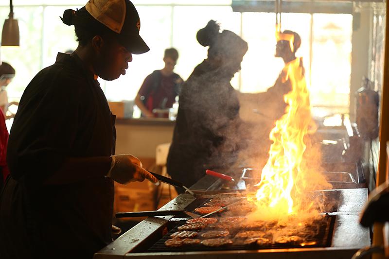 UL Lafayette dining employee flips burgers on a hot grill
