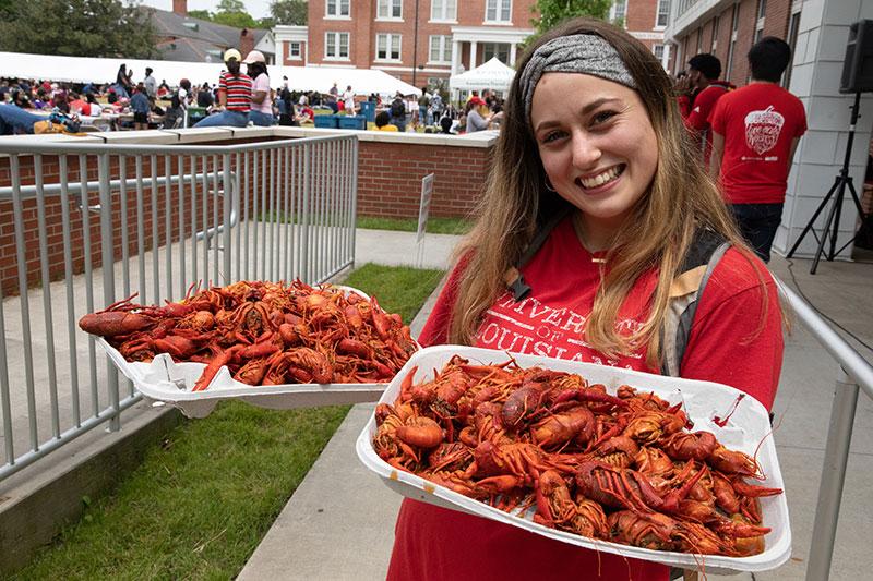 University of Louisiana at Lafayette student holding two trays of boiled crawfish during the annual tradition Lagniappe Day