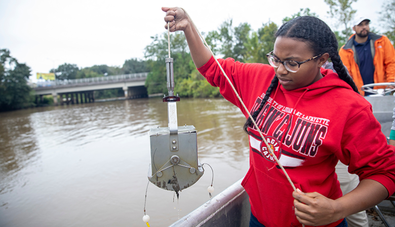 Student taking soil sample from Atchafalaya Basin