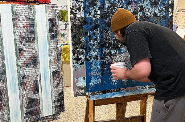 UL Lafayette painting student working on a canvas with mostly blue colors.