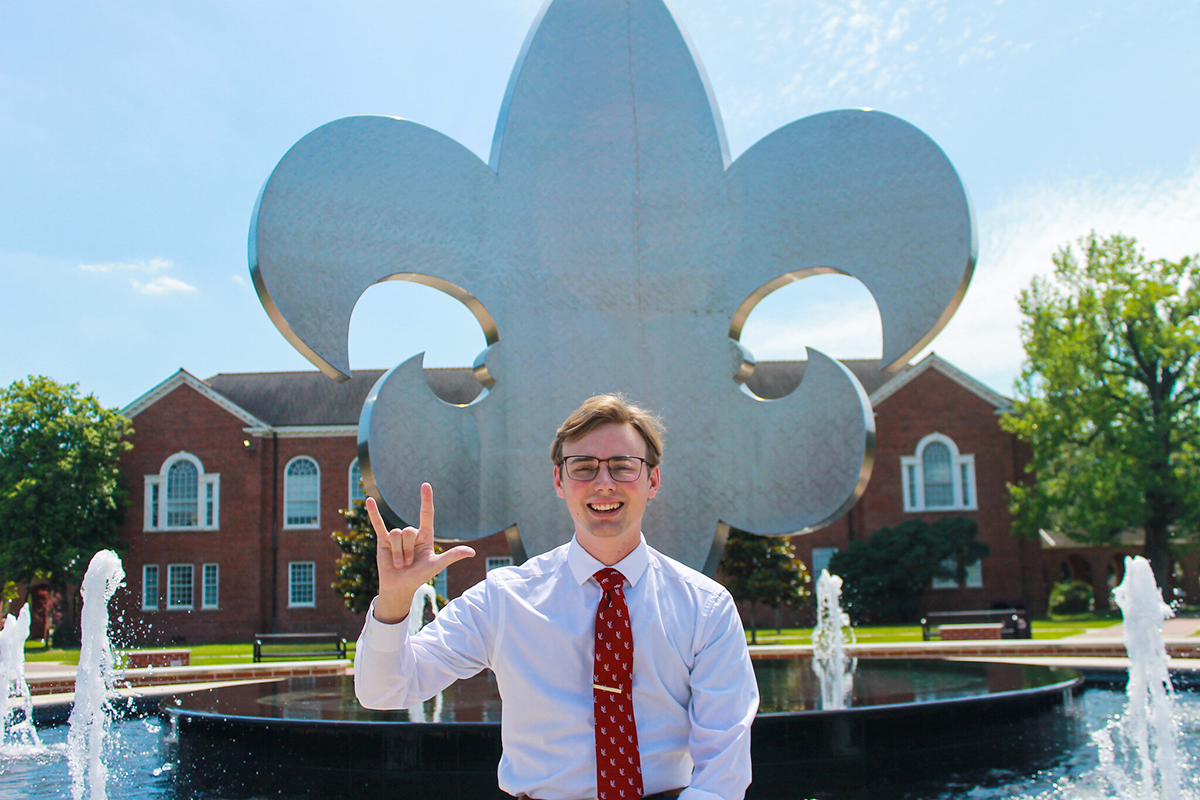 University of Louisiana at Lafayette education major Dylan Hebert in front of the iconic fleur de lis fountain in the campus quad