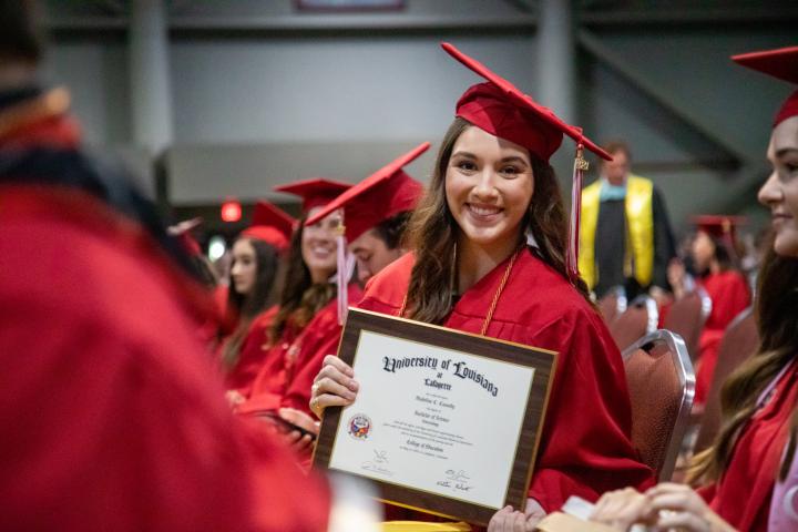 Madeline Cassedy holds up her degree plaque during commencement. Cassedy earned her degree in Health Promotion and Wellness at UL Lafayette.