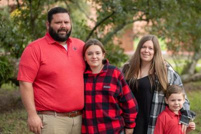 Zach Badon poses for a family photo with his wife, daughter, and son.