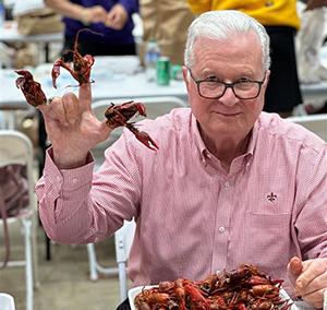 President Savoie making the UL sign with crawfish heads on his fingers at Lagniappe Day