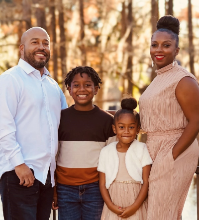 MSN graduate Shantell Dugas smiling next to her husband and two children for a family photo