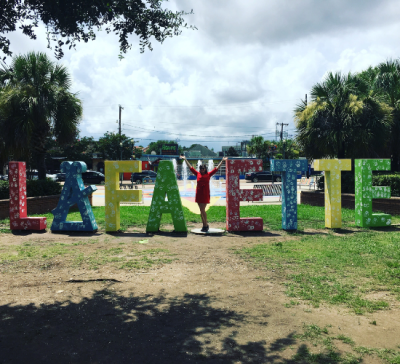 MBA graduate Kate Durio stands in place of the 'Y' in the 'Lafa-ette" sign in Downtown Lafayette.