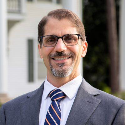 Francesco Crocco smiles for headshot in front of the Whittington House at UL Lafayette.