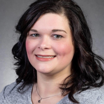 Katie Dawson smiles for headshot in front of gray background