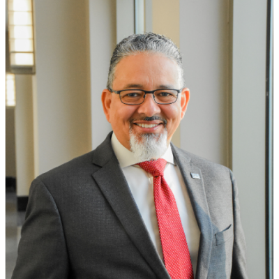 University of Louisiana System President Rick Gallot pictured in a gray suit and red tie.