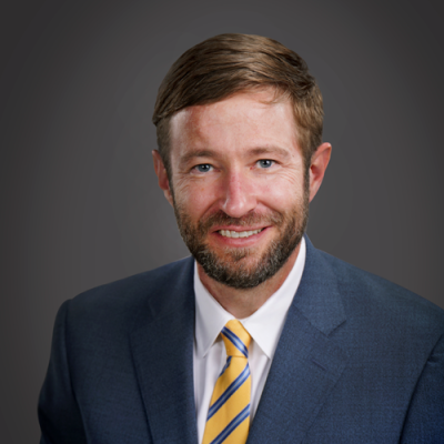 Charles Fenstermaker pictured in a blue suit and yellow striped tie.