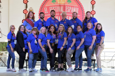 General studies online grad smiles in a group photo with the board of the New Iberia Spanish Festival.