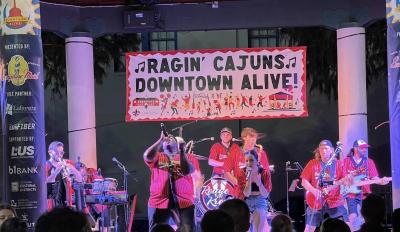 The Rouge Krewe band playing at Parc Sans Souci under the Ragin Cajuns Downtown Alive banner
