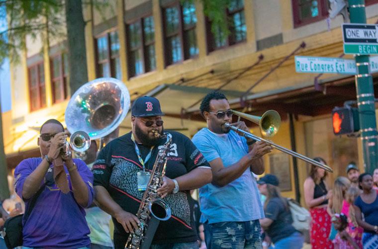 Musicians playing tuba, saxophone and trombone in downtown Lafayette during a festival